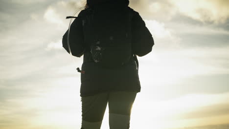 Tilting-shot-showing-a-hiker-standing-at-the-edge-taking-in-the-views-at-sunrise