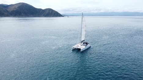 A-small-yacht-sailing-past-the-camera-with-land-in-the-background