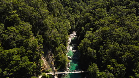 Aerial-backwards-view-of-a-lush-canyon-with-river-running-through-it