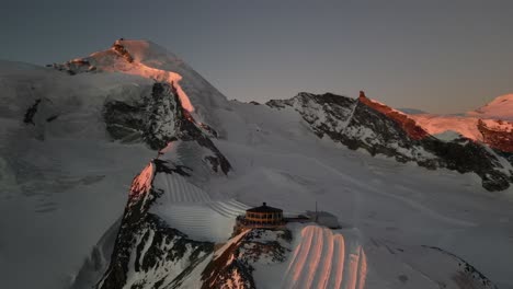 Vista-Aérea-De-Las-Montañas-En-Los-Alpes-Durante-Un-Amanecer,-Luz-Naranja-En-Las-Cumbres