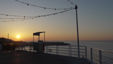 Sonnenaufgang-Im-Zeitraffer,-Wunderschöne-Küstensilhouette-Eines-Mannes,-Der-Am-Pier-Fotografiert