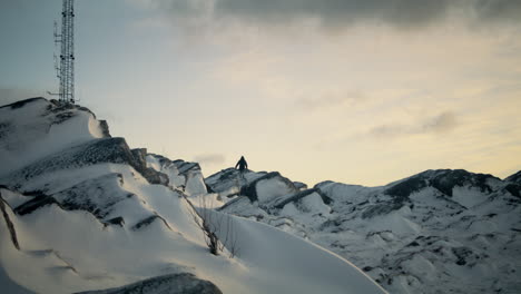 Static-shot-of-a-hiker-navigating-the-snowy-dangerous-terrain-at-the-peak-of-Lovstakken