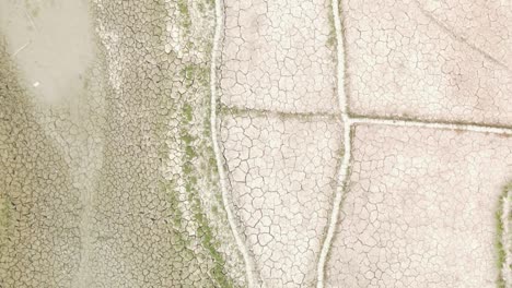 Dry-cracked-drought-fractured-agricultural-land-sections-aerial-view-over-barren-damaged-landscape