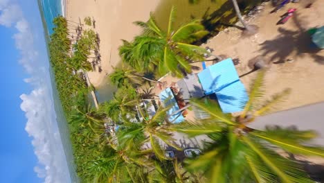 Aerial-flight-over-promenade-,-river-and-sandy-beach-with-relaxing-people-in-ARROYO-SALADO,Dominican-Republic
