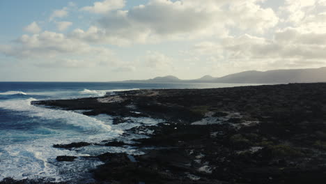 Drone-shot-of-sea-coast-in-Lanzarote-with-mountains-in-the-background