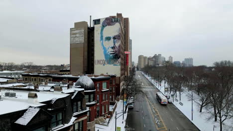 Traffic-in-front-of-the-Lincoln-mural-on-a-snowy-day-in-Chicago,-USA---Aerial-view