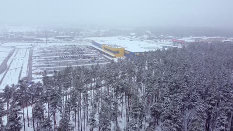 Swedish-Ikea-shop-in-winter,-forest-in-foreground,-dolly-forward-view