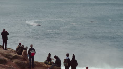 People-on-the-cliff-watching-big-crashing-waves-at-Nazare-Portugal