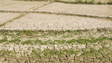 Drought-cracked-dry-fractured-agricultural-land-sections-aerial-view-rising-over-barren-damaged-landscape