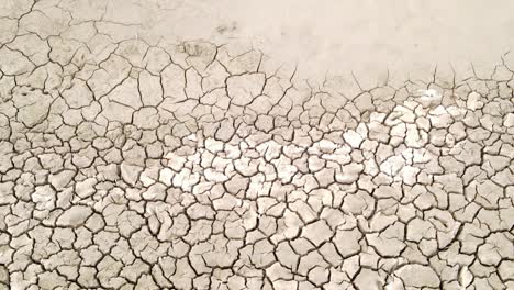 Dry-cracked-drought-fractured-land-aerial-view-descending-to-hot-barren-environment