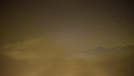 Niebla-De-Valle-Bajo-Por-La-Noche-Debajo-De-Los-Picos-De-Las-Montañas---Lapso-De-Tiempo-Con-Estrellas-En-El-Cielo