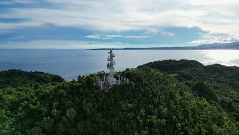 Orbiting-Aerial-view-of-birds-flying-around-Bote-lighthouse-atop-rainforest-mountain-with-vast,-pristine-ocean-and-breathtaking-clouds-in-background