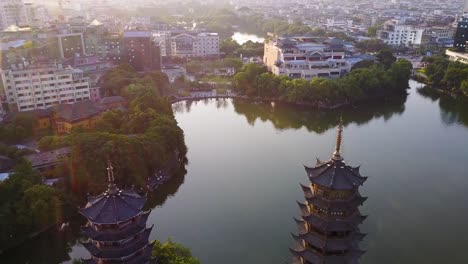 Sun-and-Moon-Pagodas-in-Guilin,-China-aerial,-with-intricate-architecture-and-the-serene-beauty-of-the-surrounding-city-and-water