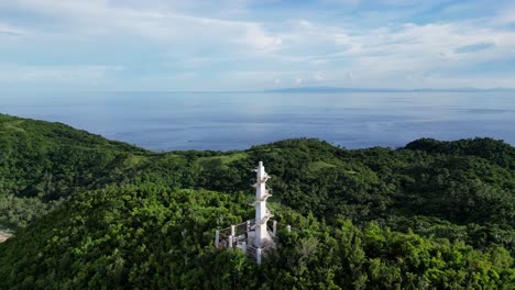 A-stunning-aerial-footage-zooms-in-and-out-on-the-Bote-Lighthouse-atop-a-foresty-hill-in-Catanduanes,-Philippines