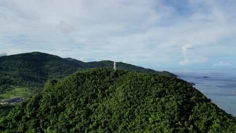 A-stunning-aerial-view-of-Bote-Lighthouse-on-a-tree-covered-mountain-in-Catanduanes,-Philippines,-surrounded-by-the-vast-ocean-and-breathtaking-natural-beauty