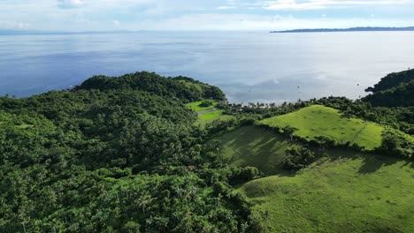 Cinematic-Aerial-View-of-lush-jungle-atop-stunning-hills-facing-breathtaking-seas-of-Bato,-Catanduanes