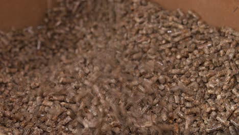wood-pellets-falling-and-piling-up-in-a-wooden-chest,-for-use-as-an-eco-friendly-renewable-organic-biofuel-or-mulch-in-the-garden