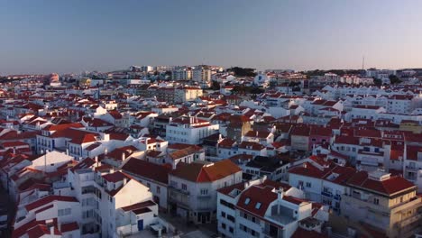 Aerial-establishing-shot-of-Waterfront-village-of-Ericeira,-A-surfing-town-in-Portuguese-Coastline,-Pullback-shot