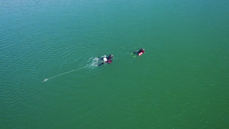 Aerial-rotating-shot-of-scuba-divers-swimming-back-to-shore-in-the-Lac-du-Crès