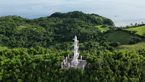 A-stunning-aerial-shot-circles-and-zooms-in-on-the-Boté-Lighthouse-perched-atop-a-lush-forestry-hill,-showcasing-its-historic-beauty-and-coastal-significance