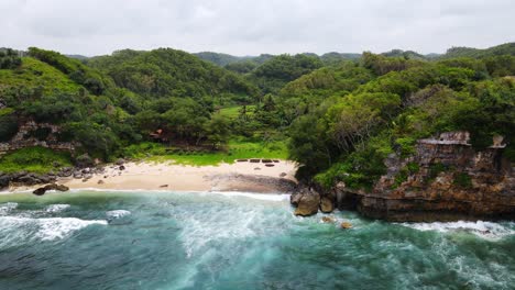 Aerial-view-of-rainforest-meeting-tropical-paradise-empty-beach-in-Indonesia