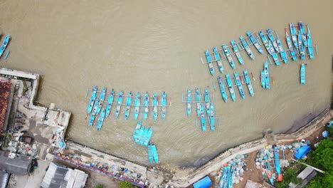 Luftaufstieg-Von-Oben-Nach-Unten-Mit-Schwerpunkt-Auf-Traditionellen-Asiatischen-Fischerbooten,-Die-Im-Schmutzigen-Fluss-Festgemacht-Sind
