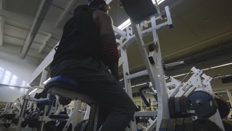 Atleta-Hombre-Fuerte-Culturista-Negro-Preparando-La-Mano-Izquierda-Para-Entrenar-Los-Músculos-De-La-Espalda-En-Equipos-Deportivos-En-4k