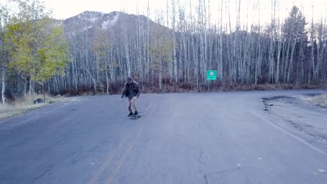 Mann-Fährt-Skateboard-Eine-Einsame-Landstraße-Im-Snow-Basin-In-Utah-Entlang