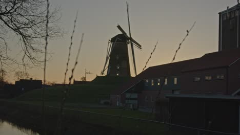 Focusrack-from-historical-windmill-in-the-Netherlands-to-reeds-near-river-at-sunset---wide
