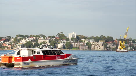 Ein-Baukranboot-Bewegt-Sich-über-Das-Wasser,-Während-Fähren-Im-Hafen-Von-Sydney,-Australien,-Vorbeifahren