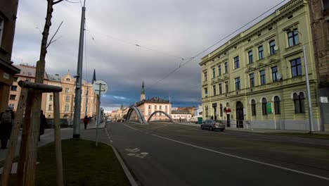 Shot-of-almost-empty-two-way-road-in-Olomouc,-Czech-Republic-on-a-cloudy-morning-with-locals-passing-by