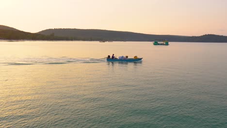 Kleines-Hölzernes-Versorgungsboot,-Das-Eine-Kleine-Bucht-überquert,-Mit-Sonnenuntergang-Im-Hintergrund