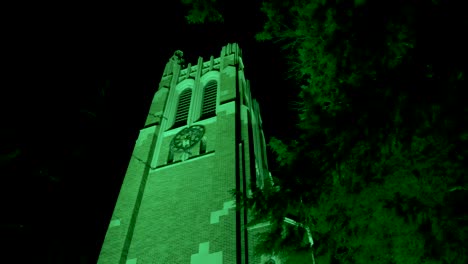 Beaumont-Tower-on-the-campus-of-Michigan-State-University-lit-up-at-night-in-green-in-honor-of-the-victims-of-the-February,-2023-mass-shooting-with-video-close-up-panning-right-to-left