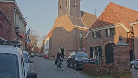 Frau-Mit-Dem-Fahrrad-Radelt-über-Einen-Kleinen-Stadtplatz-In-Der-Kleinstadt-Bredevoort