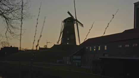 Focusrack-from-reeds-near-river-to-a-historical-windmill-in-the-Netherlands-at-sunset