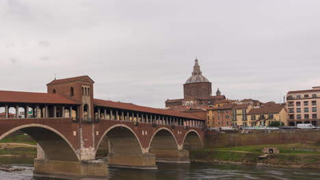 Ponte-Coperto-is-a-bridge-over-the-Ticino-river-in-Pavia,-Pavia-Cathedral-background,-time-lapse-at-cloudy-day