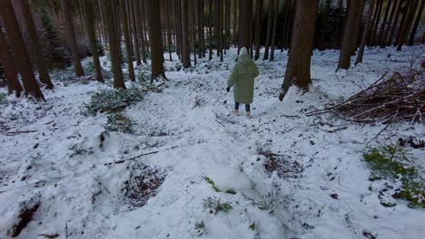 A-girl-in-a-warm-winter-jacket-is-going-down-a-snowy-hill-in-a-forest-covered-with-snow