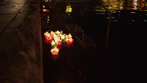 Static-shot-of-paper-candle-boats-floating-down-the-side-on-the-river-in-Hoi-An