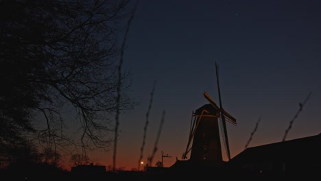 Weite-Neigung-Nach-Unten-Zur-Historischen-Windmühle-In-Der-Abenddämmerung,-Die-Eine-Wunderschöne-Landschaft-In-Den-Niederlanden-Offenbart