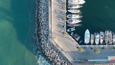 Drone-flyover-view-of-port-road-with-yachts-and-pier-,-Aerial-top-down-of-docked-sailboats