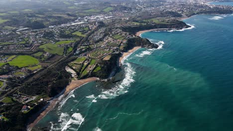 Aerial-View-of-French-Basque-Country-with-many-coastal-homes-and-green-landscapes-with-ocean-waves-breaking-at-the-surf-spots-Parlamentia-and-Guethary-close-Biarritz,-France