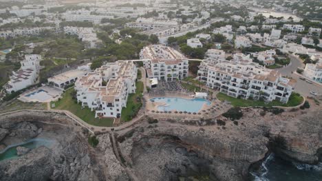 Establishing-aerial-view-rising-back-from-holiday-resort-on-coastal-cliff-edge-of-Mallorca