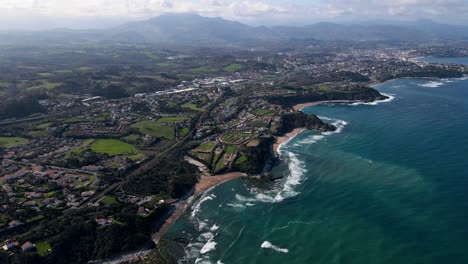 Aerial-Drone-View-of-French-Basque-Country-Coastline-close-to-Biarritz,-France-with-many-Basque-houses-in-the-coastal-towns-and-ocean-waves-breaking-on-reefs