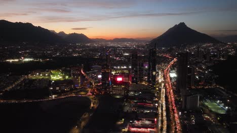 Aerial-view-of-illuminated-hi-rise-in-San-Pedro-Garza-Garcia,-Monterrey,-dusk-in-Mexico---tracking,-drone-shot