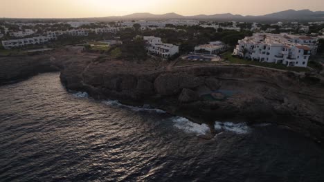Establishing-aerial-view-rising-over-Mallorca-holiday-resort-hotel-overlooking-coastal-cliff-edge