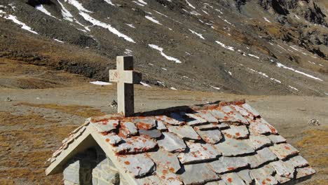 Drone-flying-around-cross-on-bell-tower-of-small-stone-church,-Col-de-l'Iseran-mountain-pass,-France