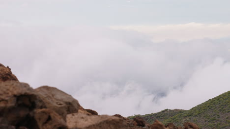4K-Slow-Motion-Mauna-Kea-Lookout-Views-Over-Cloudy-Valley-With-Rocky-Foreground