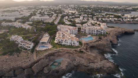 Establishing-aerial-view-rising-over-Mallorca-holiday-resort-hotel-on-cliff-edge-coastline