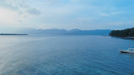 Toma-Aérea-Volando-Sobre-Un-Barco-De-Pesca-Antes-Del-Amanecer-Al-Amanecer-Sobre-Aguas-Tranquilas-En-Bali,-Indonesia
