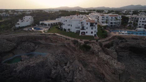 Establishing-aerial-view-orbiting-Mallorca-holiday-resort-hotel-overlooking-coastal-cliff-edge